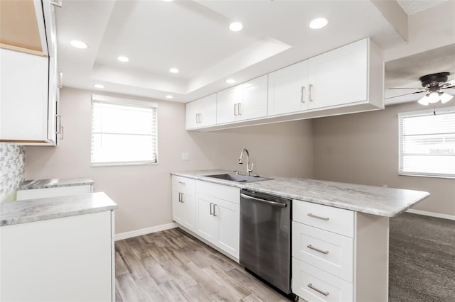 kitchen featuring sink, white cabinets, stainless steel dishwasher, kitchen peninsula, and a raised ceiling