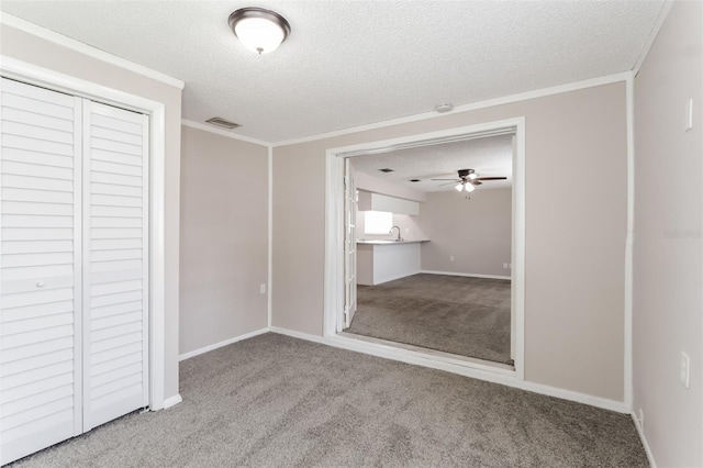 unfurnished bedroom featuring ornamental molding, a closet, a textured ceiling, and carpet