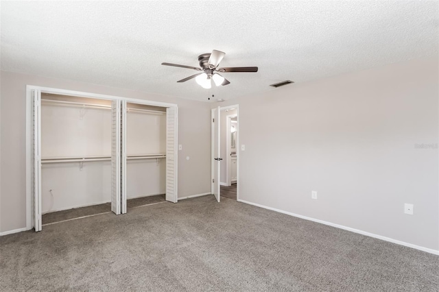 unfurnished bedroom with ceiling fan, a textured ceiling, carpet floors, and multiple closets