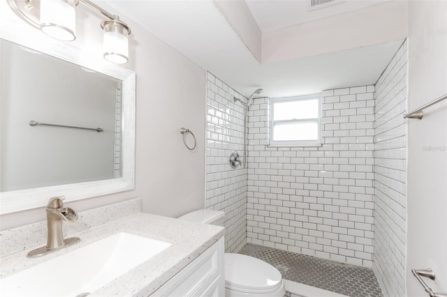 bathroom featuring tiled shower, vanity, and toilet