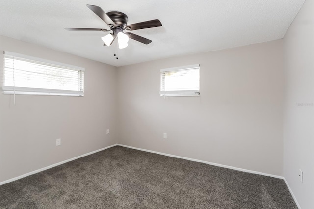 unfurnished room featuring plenty of natural light, ceiling fan, and dark colored carpet