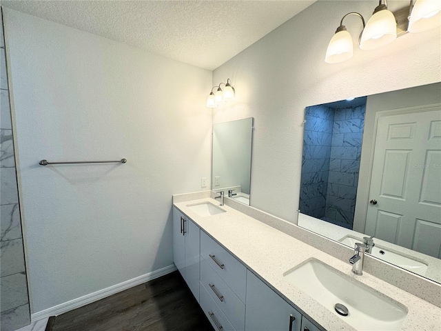 bathroom featuring hardwood / wood-style flooring, double sink vanity, and a textured ceiling