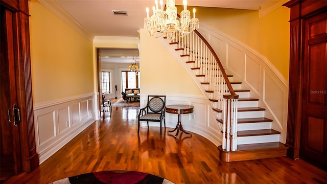 staircase featuring a chandelier, crown molding, and hardwood / wood-style floors