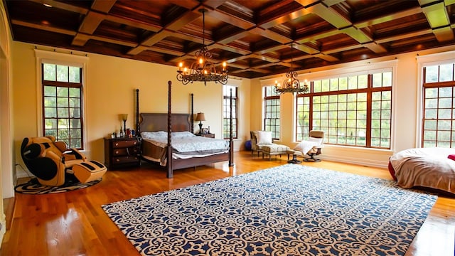 bedroom with hardwood / wood-style floors, beamed ceiling, a notable chandelier, and coffered ceiling