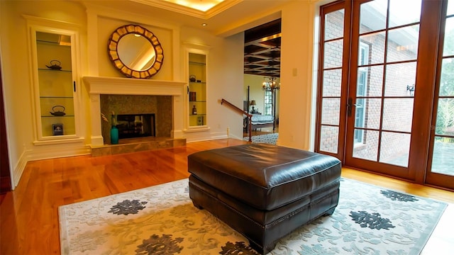 living room featuring ornamental molding, built in shelves, a notable chandelier, and hardwood / wood-style floors