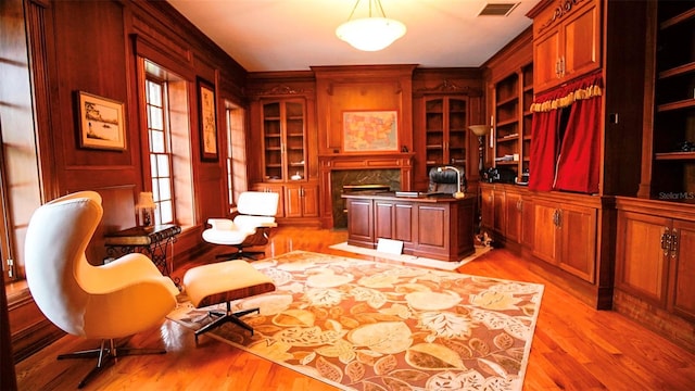 home office with built in features, light hardwood / wood-style flooring, and a premium fireplace