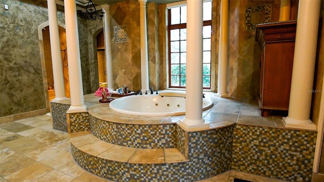 bathroom with a relaxing tiled tub, tile patterned floors, and ornate columns