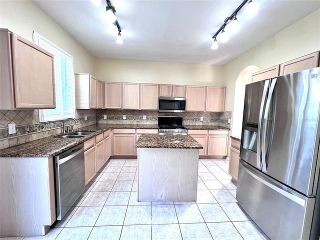 kitchen with light tile patterned flooring, a sink, appliances with stainless steel finishes, a center island, and light brown cabinetry