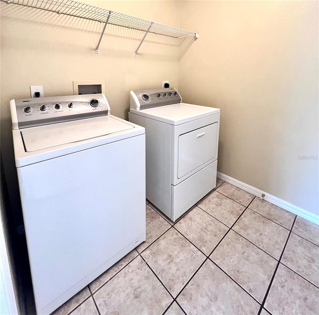 clothes washing area featuring light tile patterned floors, laundry area, washer and clothes dryer, and baseboards