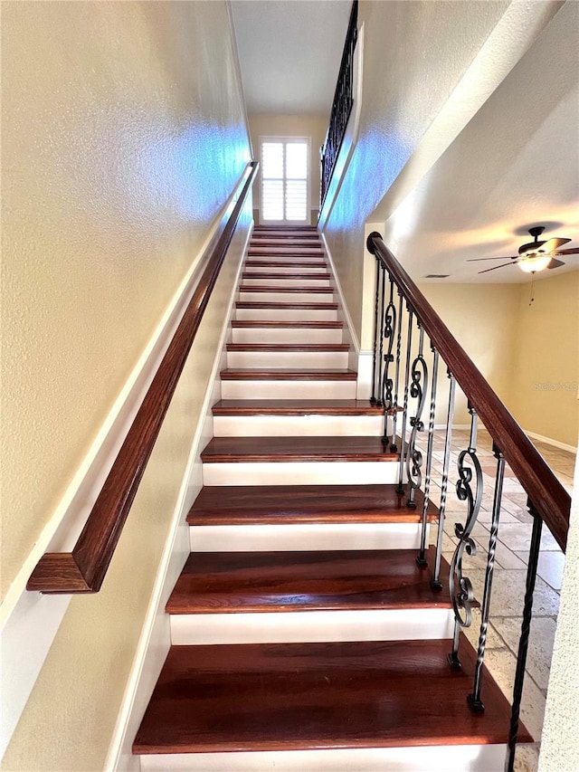 stairs with baseboards, a ceiling fan, and a textured wall