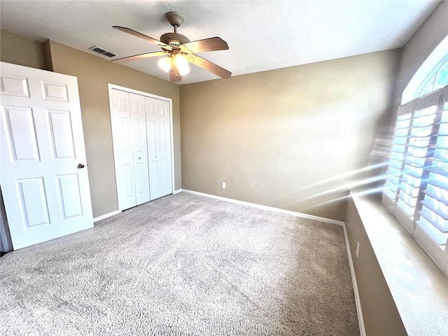 unfurnished bedroom featuring baseboards, visible vents, a ceiling fan, carpet flooring, and a closet