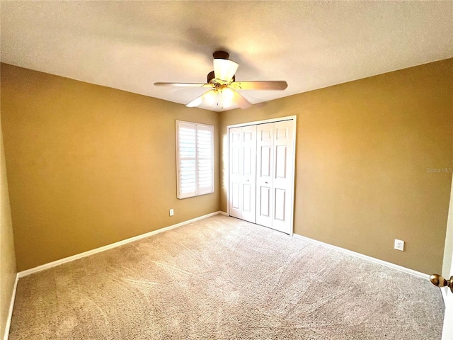 unfurnished bedroom with baseboards, a ceiling fan, a textured ceiling, carpet floors, and a closet