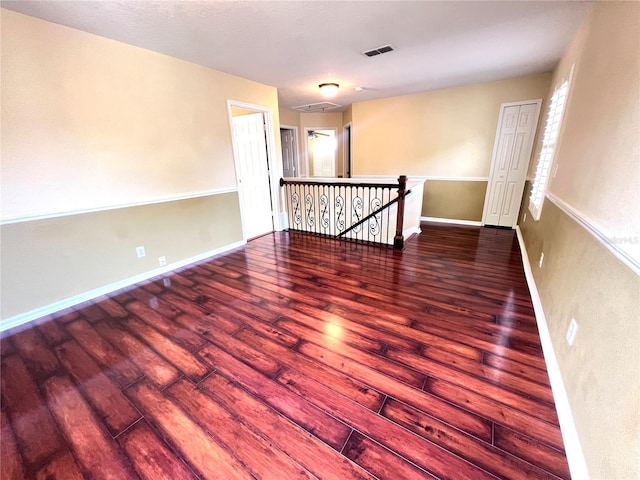 spare room with visible vents, baseboards, and wood finished floors