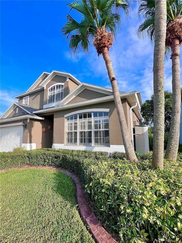 view of front of home featuring a garage, a front yard, and stucco siding