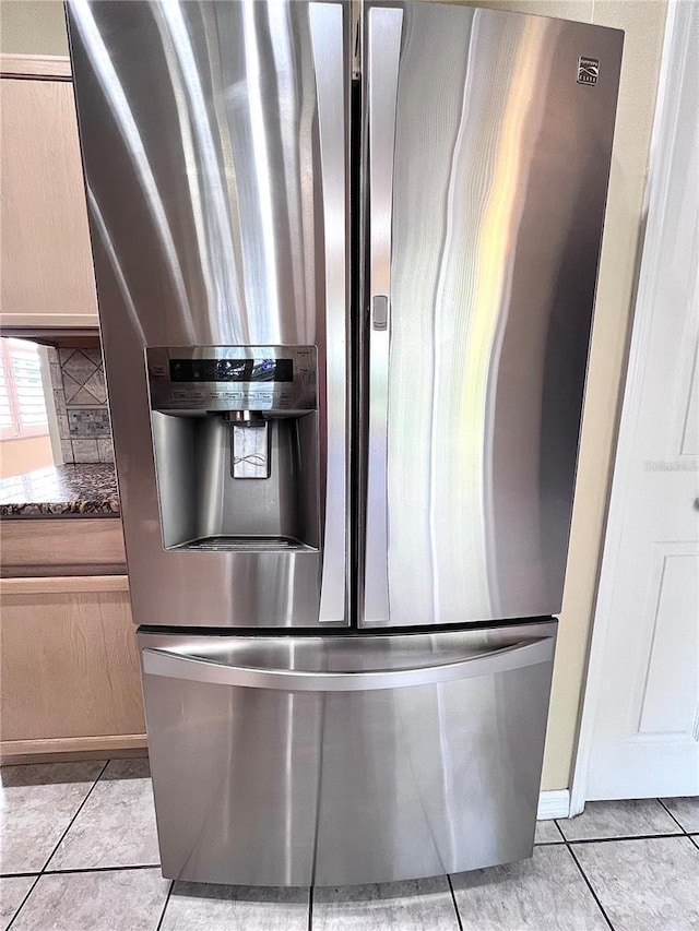 room details with light brown cabinets, backsplash, dark stone countertops, and stainless steel fridge