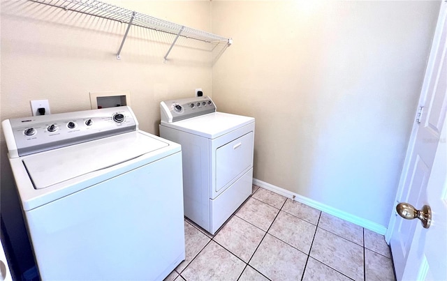 clothes washing area with washing machine and dryer, laundry area, baseboards, and light tile patterned floors