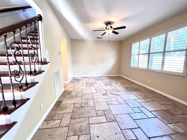 interior space with visible vents, baseboards, stone tile floors, and a ceiling fan