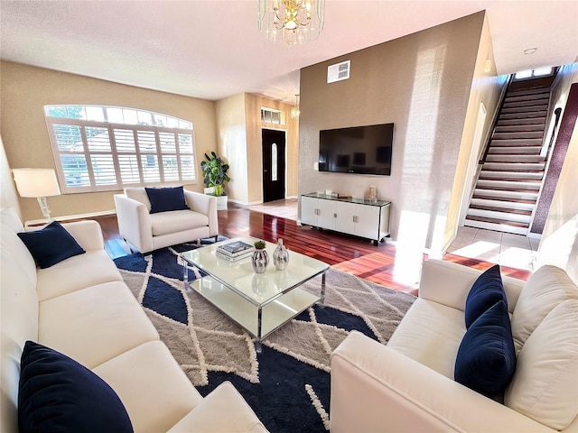 living room with a chandelier, visible vents, stairway, and wood finished floors