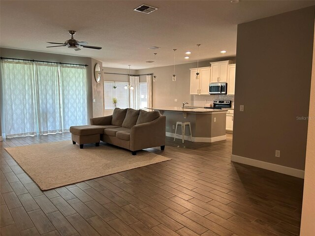 living room featuring sink, ceiling fan, and dark wood-type flooring