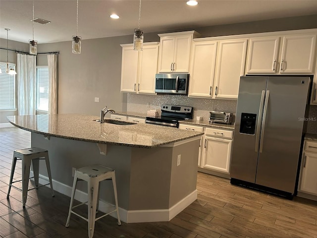 kitchen with sink, appliances with stainless steel finishes, hardwood / wood-style flooring, and a center island with sink