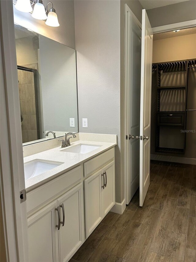 bathroom featuring walk in shower, wood-type flooring, and double sink vanity