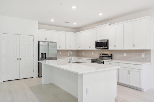 kitchen with white cabinetry, a kitchen island with sink, sink, and appliances with stainless steel finishes