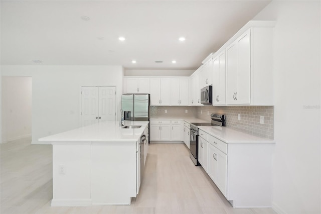 kitchen with backsplash, a center island with sink, white cabinets, sink, and stainless steel appliances