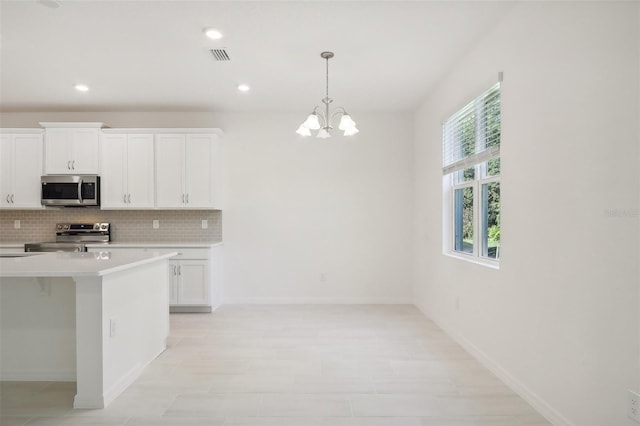 kitchen featuring decorative light fixtures, decorative backsplash, white cabinetry, and appliances with stainless steel finishes