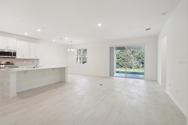 kitchen with plenty of natural light, a kitchen breakfast bar, white cabinetry, and stainless steel appliances