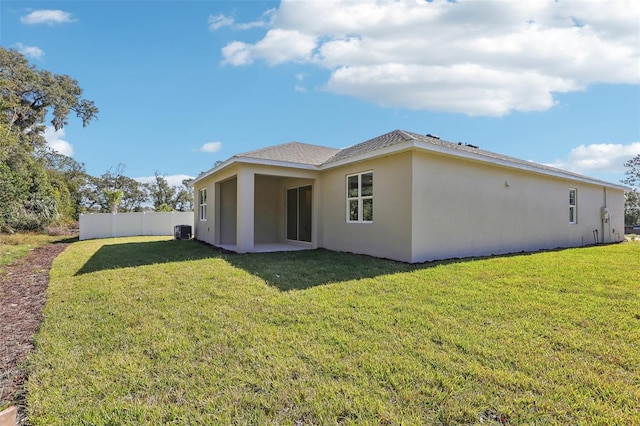 rear view of property featuring cooling unit and a yard