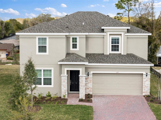 view of front of property featuring decorative driveway, stone siding, a shingled roof, and stucco siding