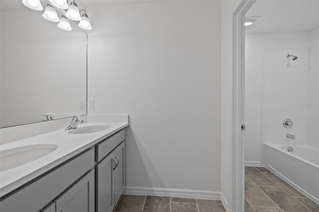 bathroom with double vanity, shower / bath combination, a sink, and baseboards