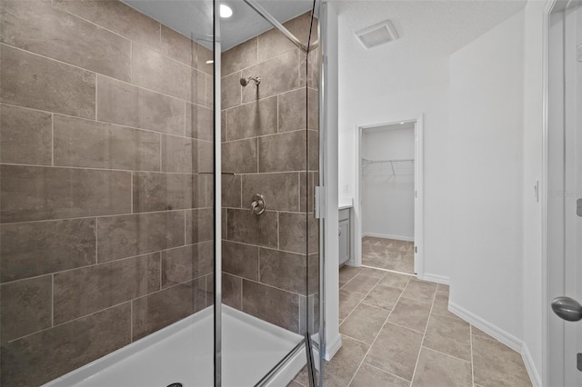 bathroom featuring tile patterned flooring, visible vents, baseboards, a spacious closet, and a shower stall