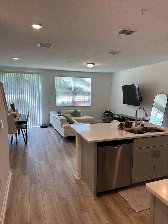 kitchen featuring stainless steel dishwasher, sink, a textured ceiling, and light hardwood / wood-style floors