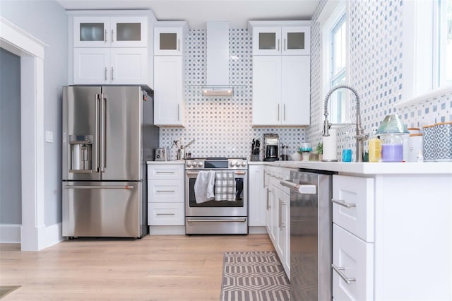 kitchen with white cabinetry, appliances with stainless steel finishes, light hardwood / wood-style floors, and decorative backsplash