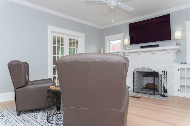 interior space featuring a brick fireplace, ornamental molding, light hardwood / wood-style floors, and ceiling fan