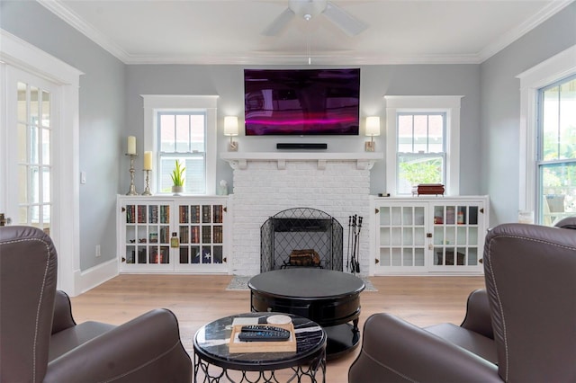 living room featuring a brick fireplace, crown molding, light hardwood / wood-style flooring, and a wealth of natural light