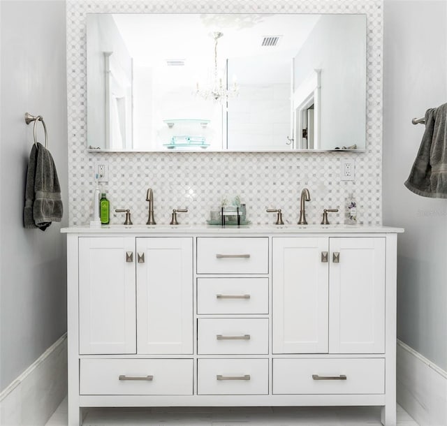 bathroom featuring tasteful backsplash, vanity, and a notable chandelier