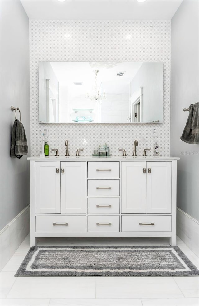 bathroom with an inviting chandelier, decorative backsplash, tile patterned floors, and vanity