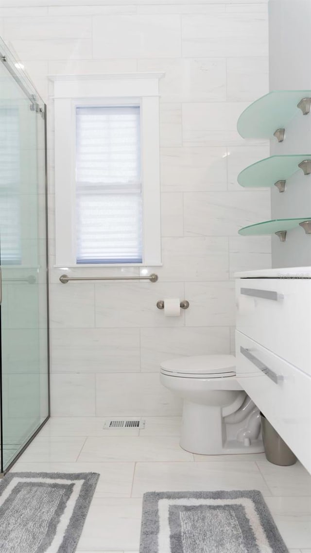 bathroom with tile walls, vanity, a shower with shower door, and toilet