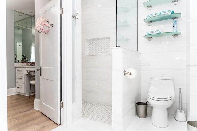 bathroom with hardwood / wood-style flooring, tiled shower, tile walls, and toilet