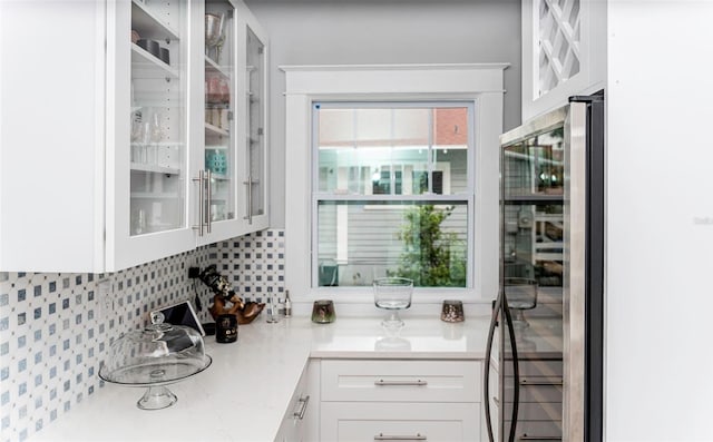 kitchen featuring white cabinetry, decorative backsplash, and beverage cooler