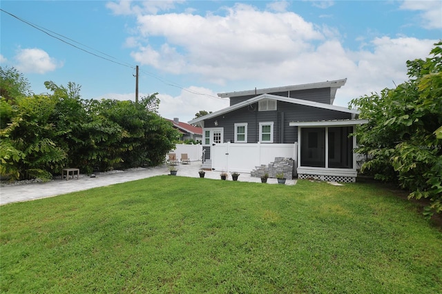 rear view of property with a sunroom and a lawn