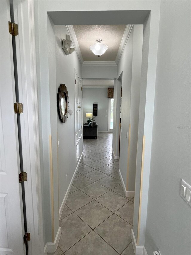 corridor with light tile patterned flooring, crown molding, and a textured ceiling