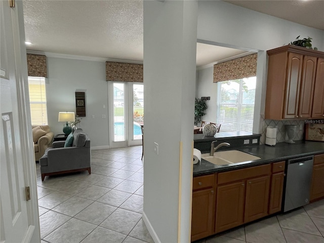 kitchen with a sink, open floor plan, dishwasher, brown cabinetry, and dark countertops