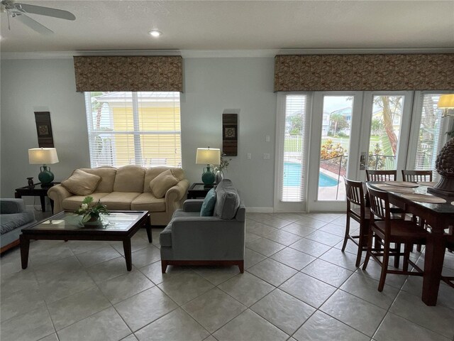 living room featuring light tile patterned flooring, ornamental molding, and ceiling fan