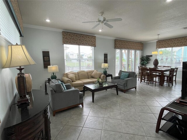 living room with light tile patterned flooring, crown molding, ceiling fan, and a textured ceiling