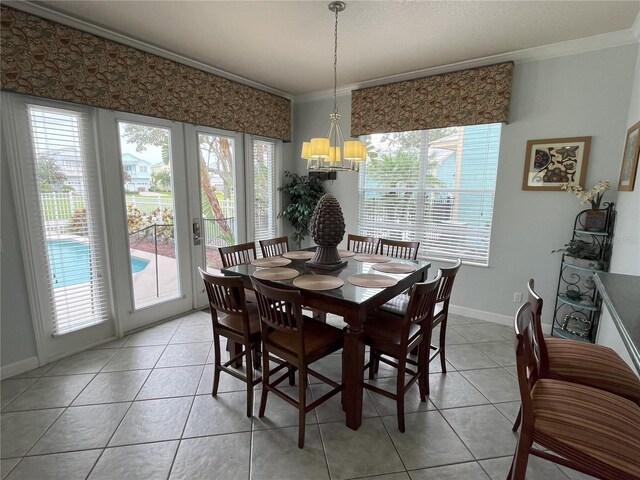 dining room with french doors, crown molding, an inviting chandelier, and light tile patterned floors