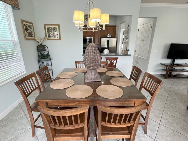 tiled dining space featuring ornamental molding, a notable chandelier, and a wealth of natural light