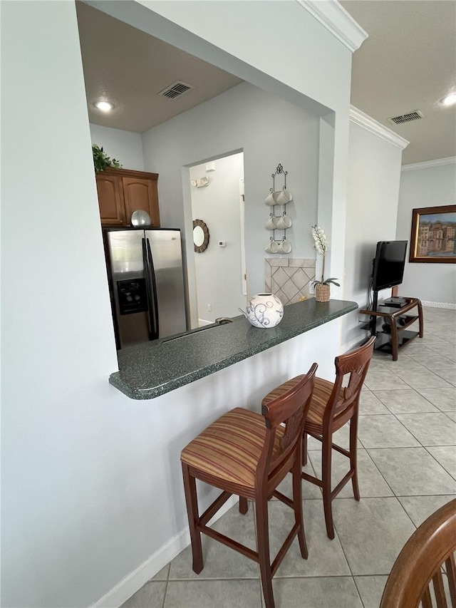 kitchen featuring ornamental molding, stainless steel fridge, light tile patterned floors, and kitchen peninsula